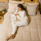woman laying in bed wearing hug sleep loungewear in cream cream