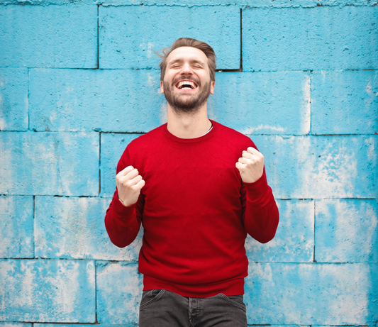 Image of man standing in front of a wall happy and excited