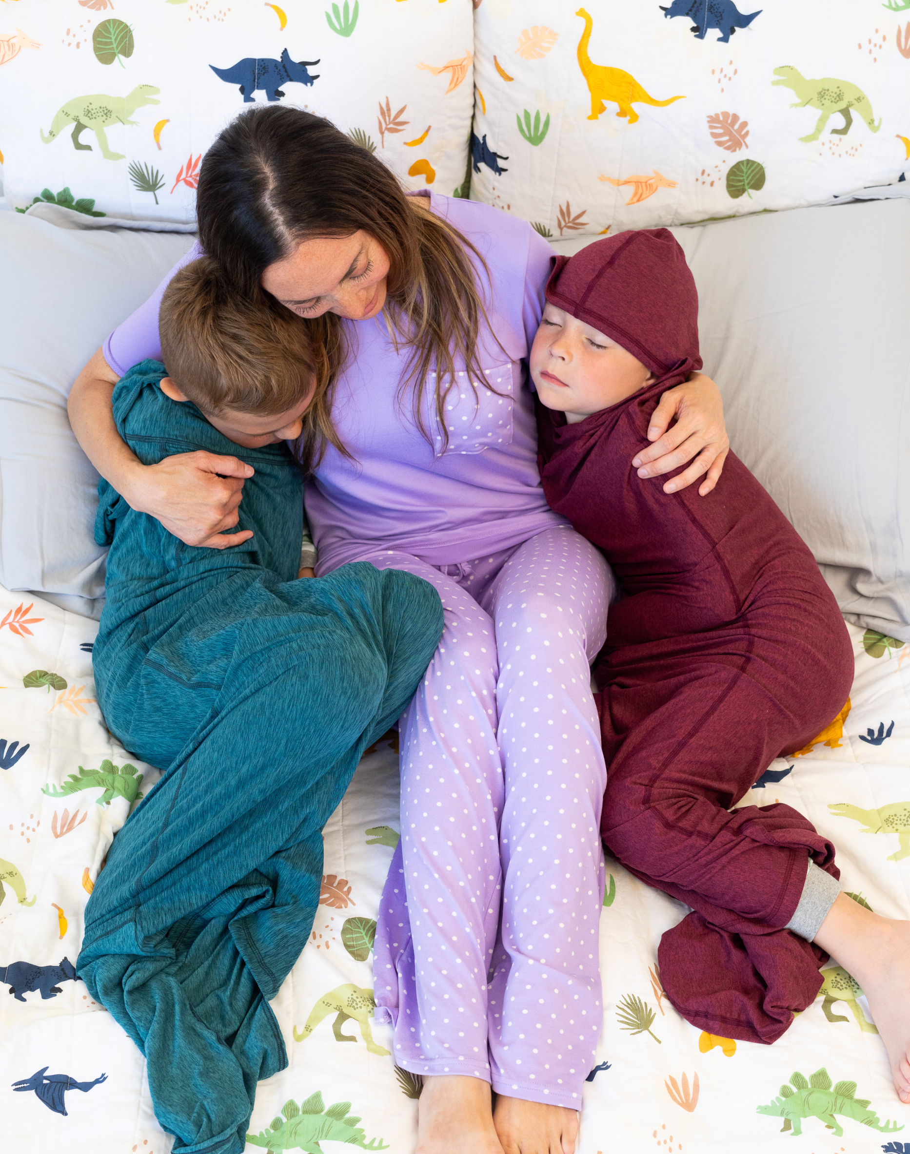 Woman holding two sleeping children on bed