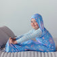 Child sleeping on a bed in a blue star-patterned hooded Sleep Pod.
