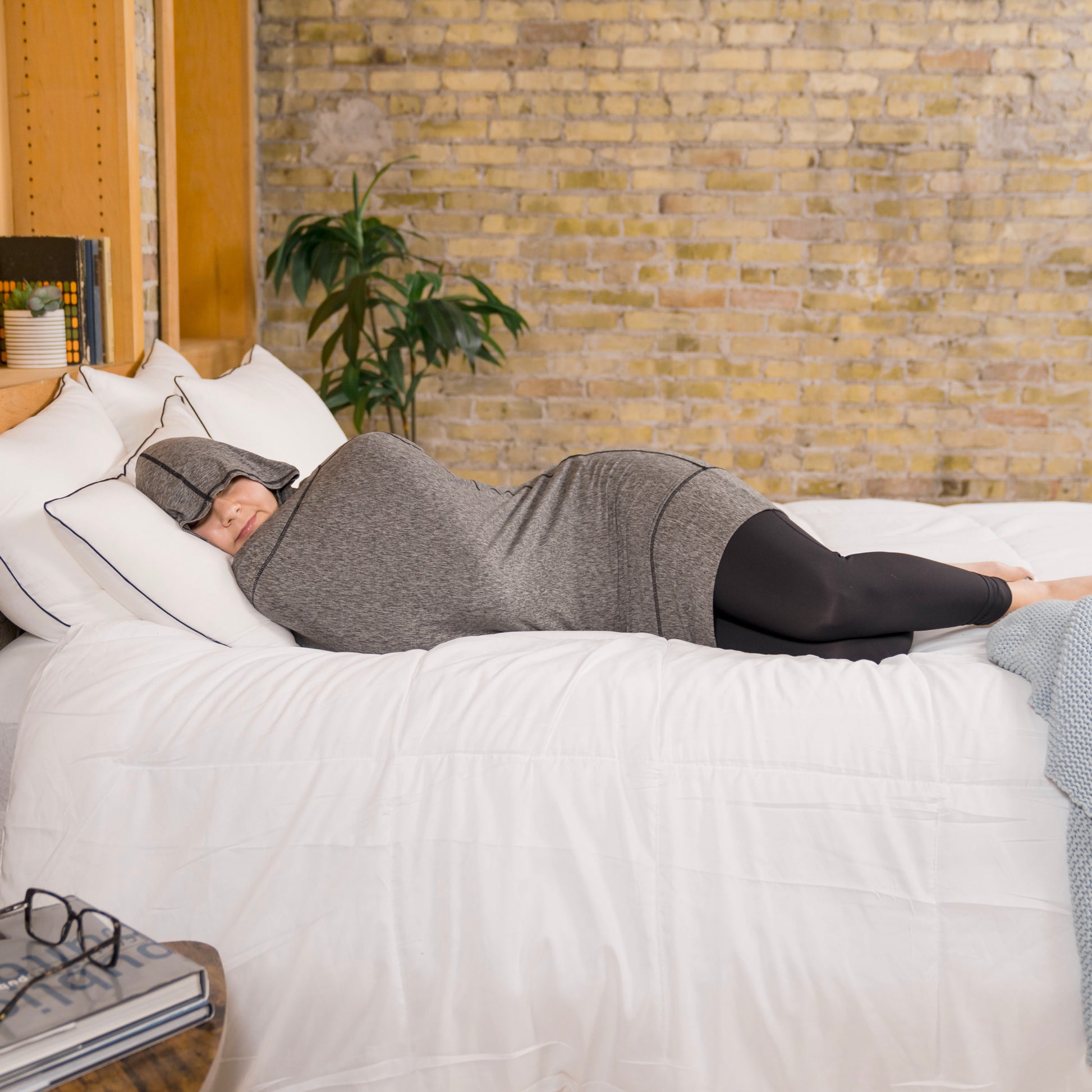woman on bed in hug sleep pod mini sleeping with hood up over head
