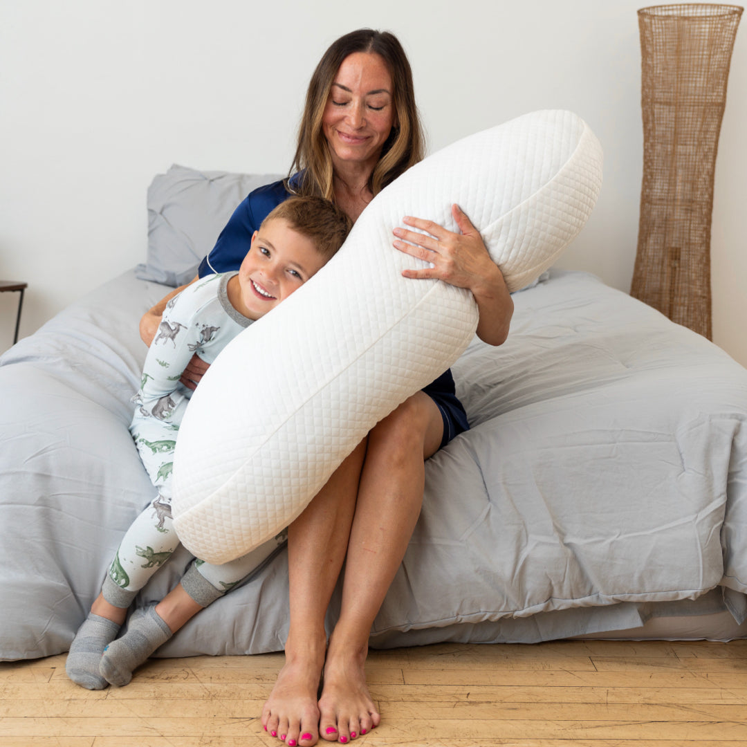 woman sitting down hugging body pillow with child