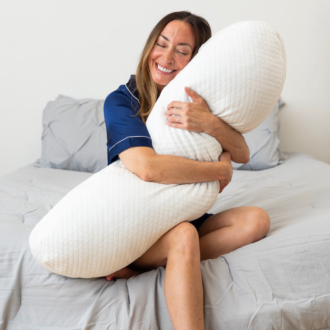 woman sitting down hugging body pillow