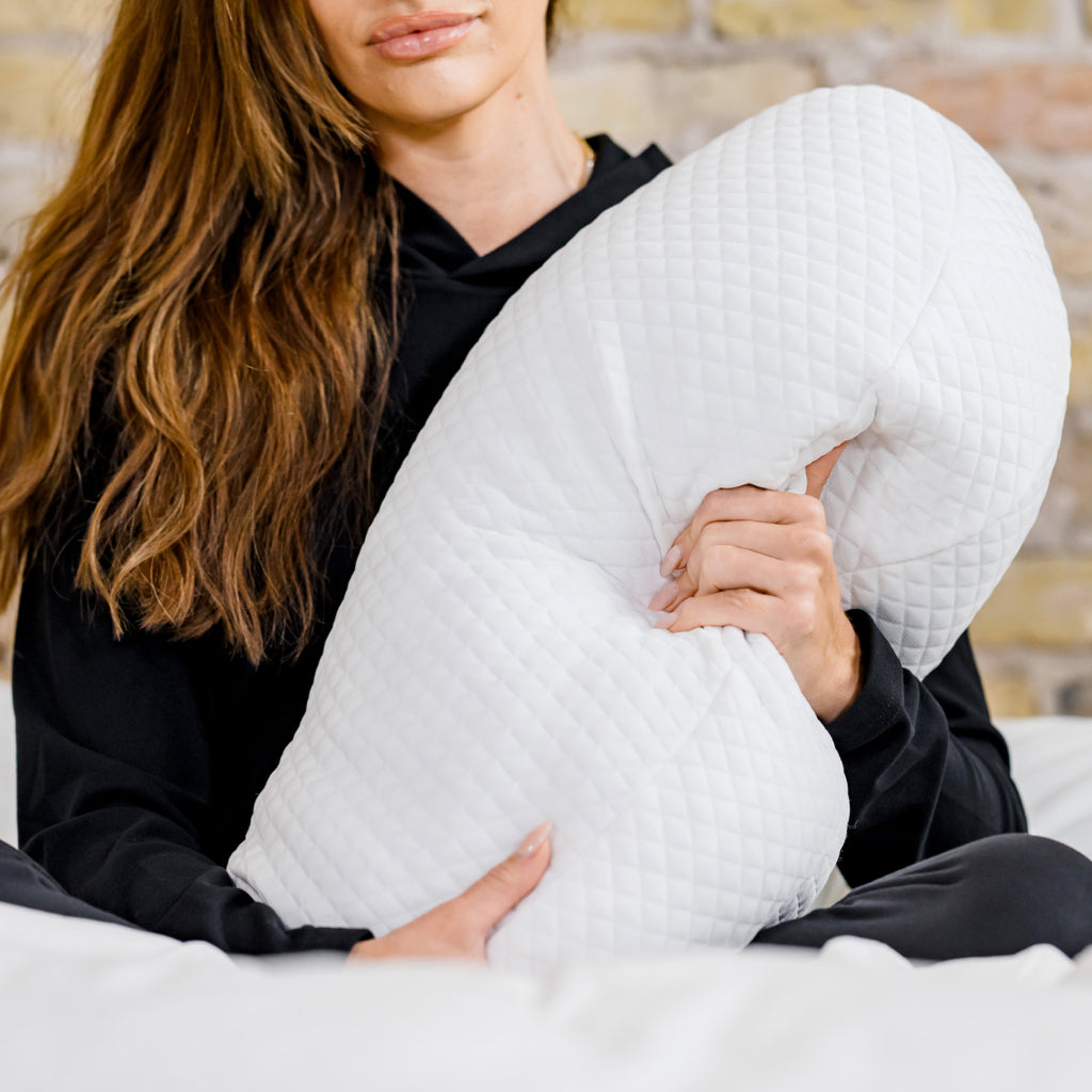 woman sitting down hugging body pillow