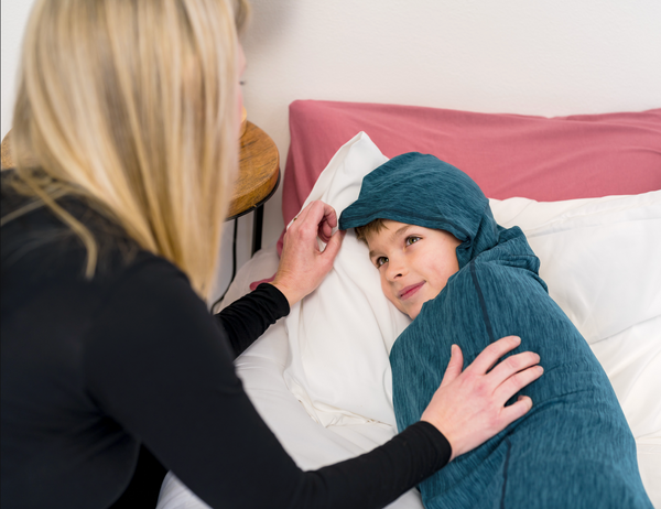 Mother tucking her child into a sleep pod in bed