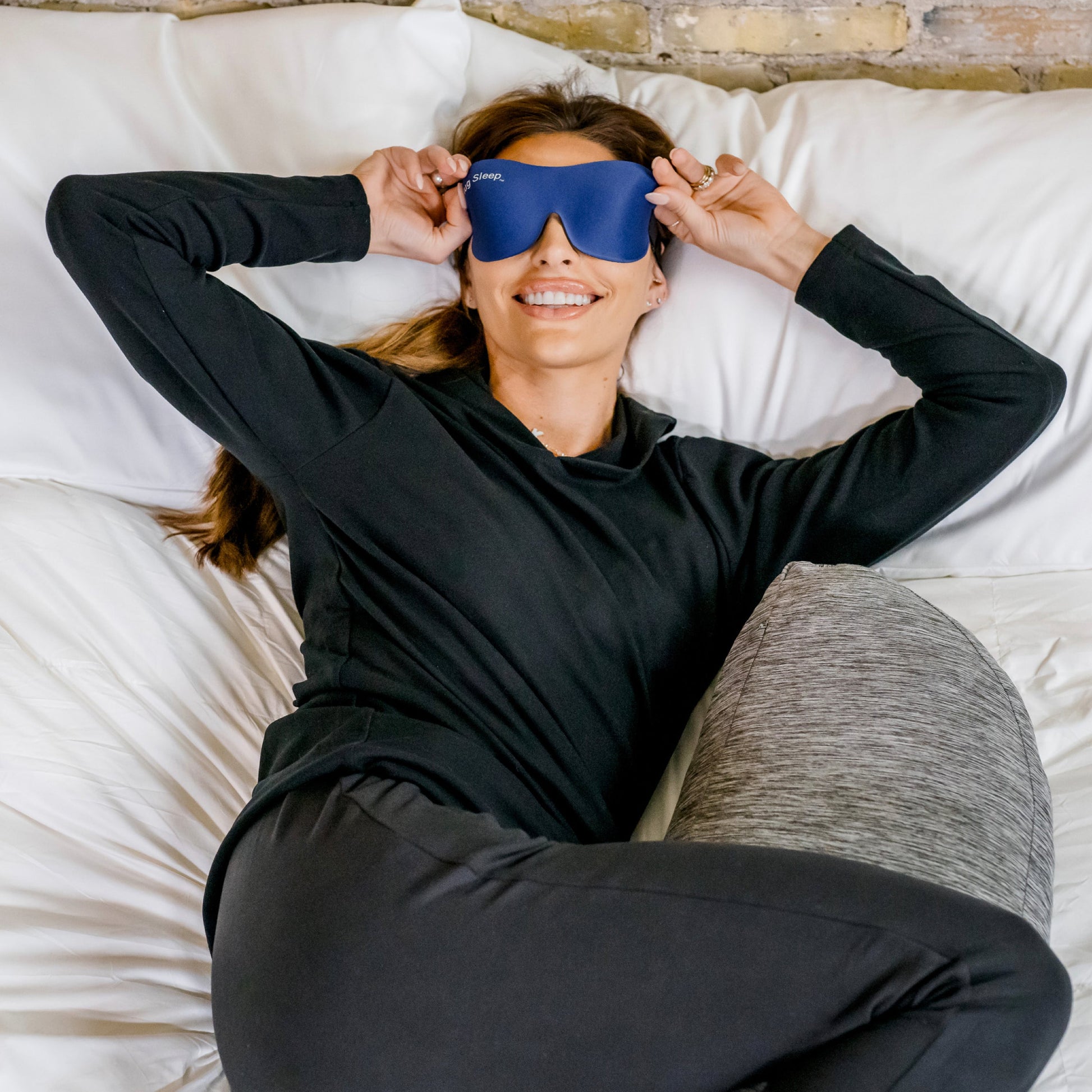 woman in bed waking up with the hug sleep mask on