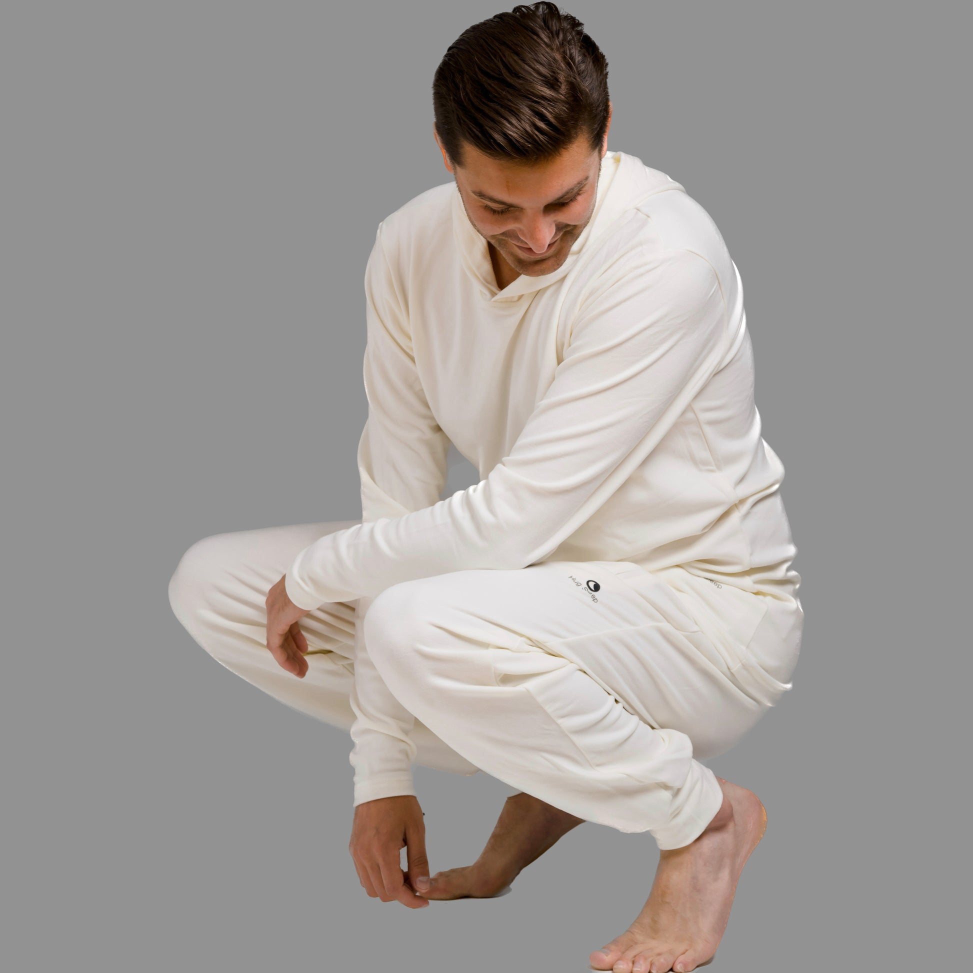 man squatting down wearing hug sleep loungewear in cream cream
